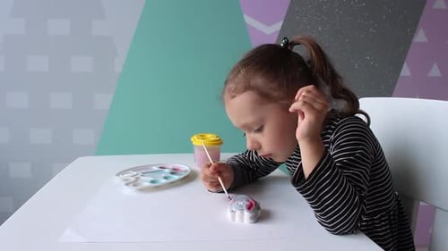 Girl Paints Decorative Figure at Table