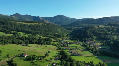 drone flight in a valley seeing a village with its white houses with red roofs, crop fields and thei