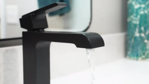 Modern Black Faucet Dispensing Water in Bathroom Sink