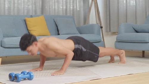 Asian Teenager Boy Doing Pushups On Mat With Dumbbells During The Shirtless Workout At Home