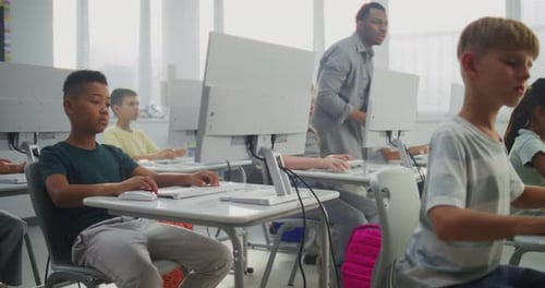 Primary School Students Working on Computers Teacher Guiding Diverse Kids in Studying Programming