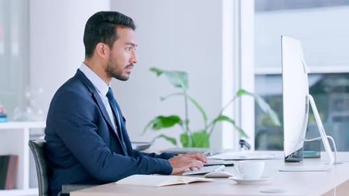 Business man typing and browsing on a computer while working in an office