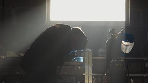 Silhouette of Worker Welding Metal Parts in Workshop