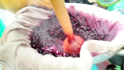 Crushing cooked cherries with a wooden pestle