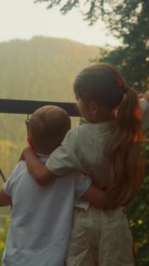 Sister Hugs Brother Watching Lake Surrounded By Forest