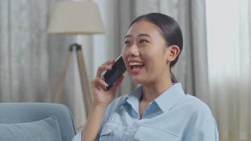 Close Up Of Asian Woman Talking On Smartphone While Lying On Sofa In The Living Room