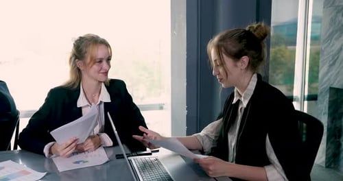 Business Women Discuss Charts and Documents at Meeting