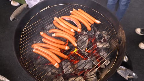 Frankfurters Cooking on a Round Charcoal Grill