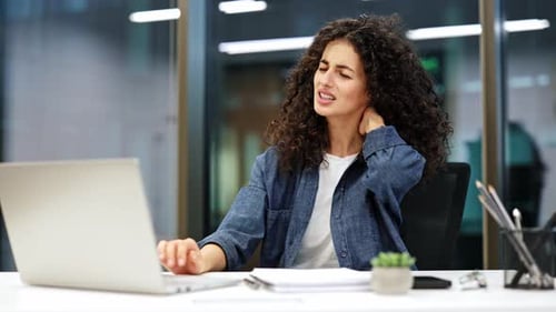 Businesswoman with Neck Pain Working on Laptop in Office