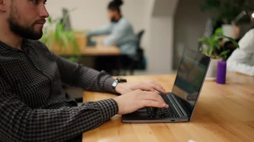 Businessman Working on Laptop Late in Office with Coworkers