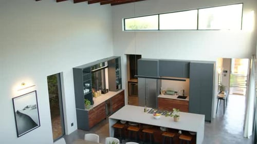 Modern kitchen with island, dining table, and bar stools in contemporary home, copy space