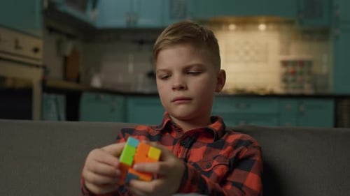 Focused Boy Solving Rubik's Cube Puzzle Indoors