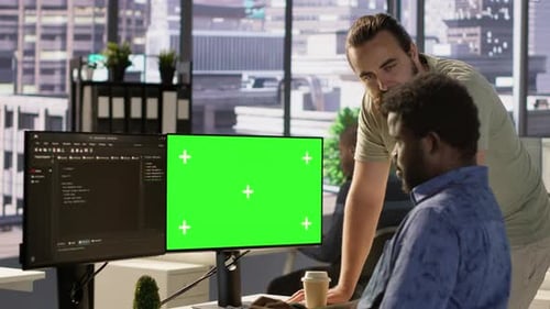 Admin macht Software-Debugging auf einem Greenscreen-PC mit einem Kollegen
