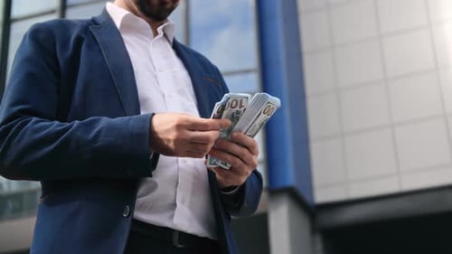 Erfolgreicher Geschäftsmann in Anzug zählt Bargeld, Geld, Dollar, Gewinn, Vermögen, Ersparnisse in der Innenstadt, Nahaufnahme