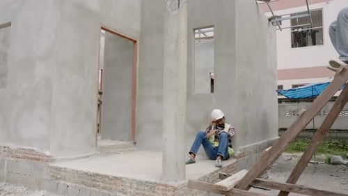 indian man foreman engineer housing project building construction frame Sitting against wall facing