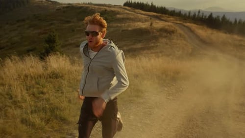 Fit Sportsman Running Fast on Dirty Road. Athletic Man Jogging in Mountains