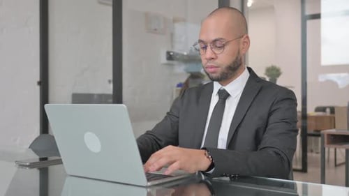 Young Adult Typing on Laptop in Modern Office