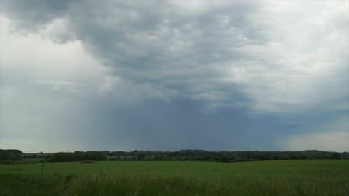 dark thunderclouds pass the camera in fast motion across green fields