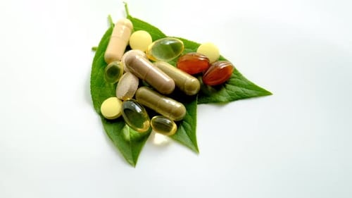 Supplements and Pills on Green Leaf Background