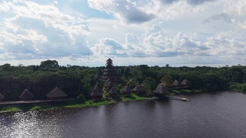 Aerial View of Wooden Thatched Bungalows Blending with Verdant Jungle Alongside Winding Amazon River