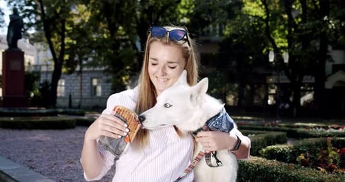 Blonde Woman Shares Sandwich with White Husky Dog