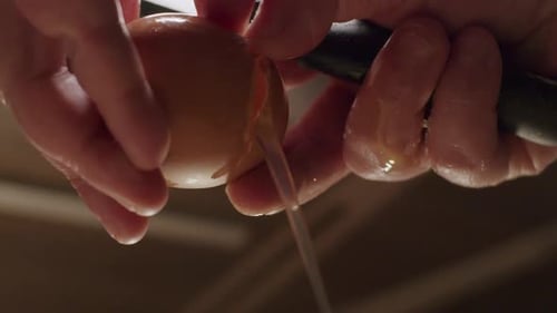 A person hands cracking open a egg with egg white and yellow yolk pouring out in slow motion, close