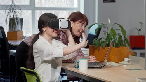 Two Female Colleagues Joyfully Exploring 3D VR Glasses at the Office
