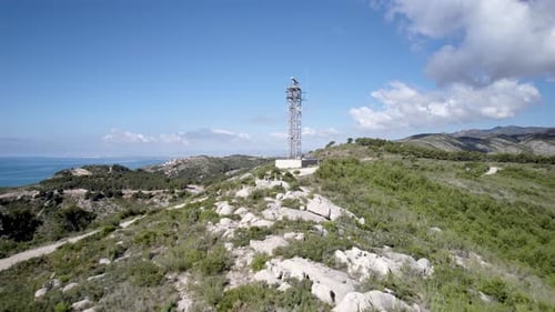 Aerial view of Marine Radar antenna spinning on top of a hill in front of the Mediterranean Sea on t