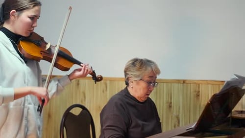 Girl Plays Violin with Senior Woman Plays Piano