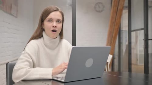 Woman Expressing Emotion While Using Laptop Indoors