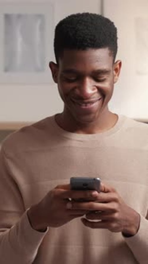 Smiling Man Using Mobile Phone Indoors