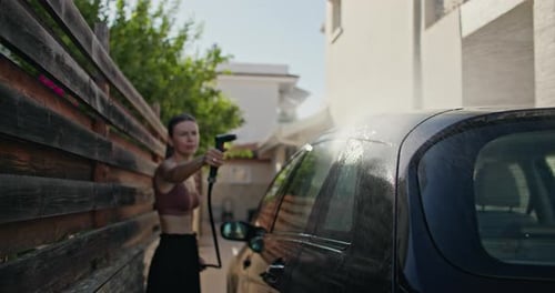 Woman Washes Car in Driveway on Sunny Day