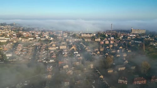 Cinematic aerial view of town city with residential buildings in earning fog and mist.