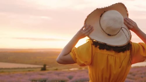 Femme dans un champ appréciant l'aromathérapie à la lavande, beau fond, fleurs violettes, robe jaune, paix