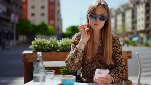 Female Professional Resting at Sidewalk Cafe Drinking Cappuccino Checking Social Media Wearing