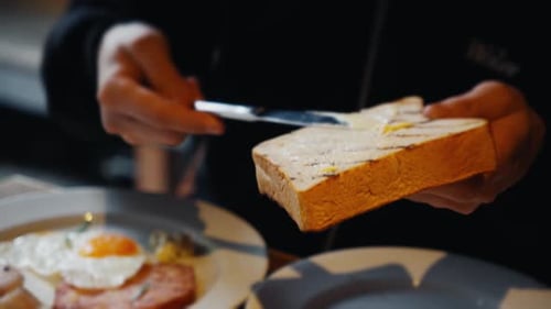 Man Spreads Butter on Toast for Breakfast Meal