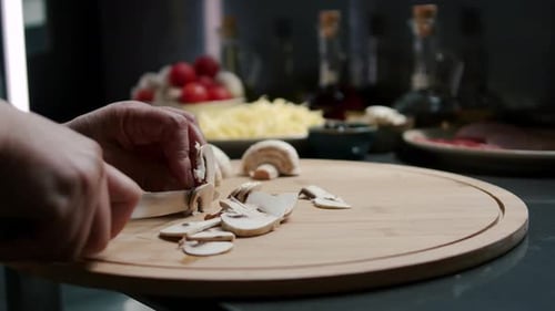 A woman cuts mushrooms on a cutting board. Preparing the pizza