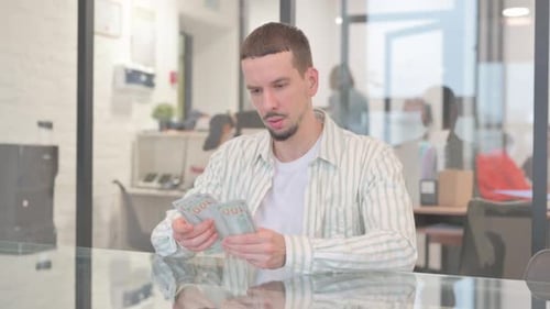 Creative Young Man Counting Money in Office