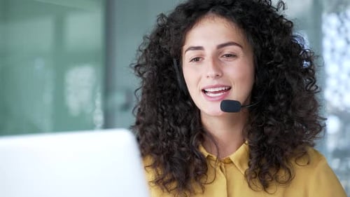 Smiling Woman with Headset Talking at Computer