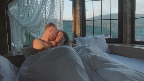 Couple Cuddling on Bed in Morning