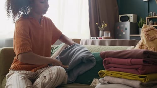 Woman Folding Clothes in Living Room