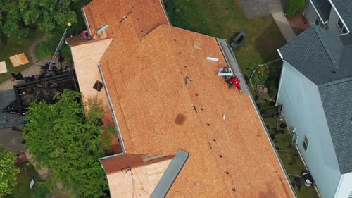 Roofers Installing a New Roof on an Residential Building Aerial Drone Wide Footage