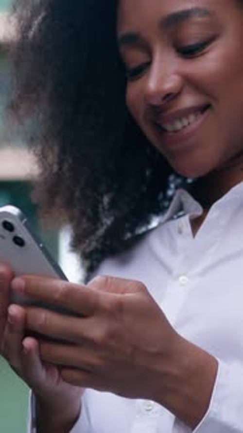 Smiling African American Business Woman Using Mobile Phone Chatting Online in City Businesswoman