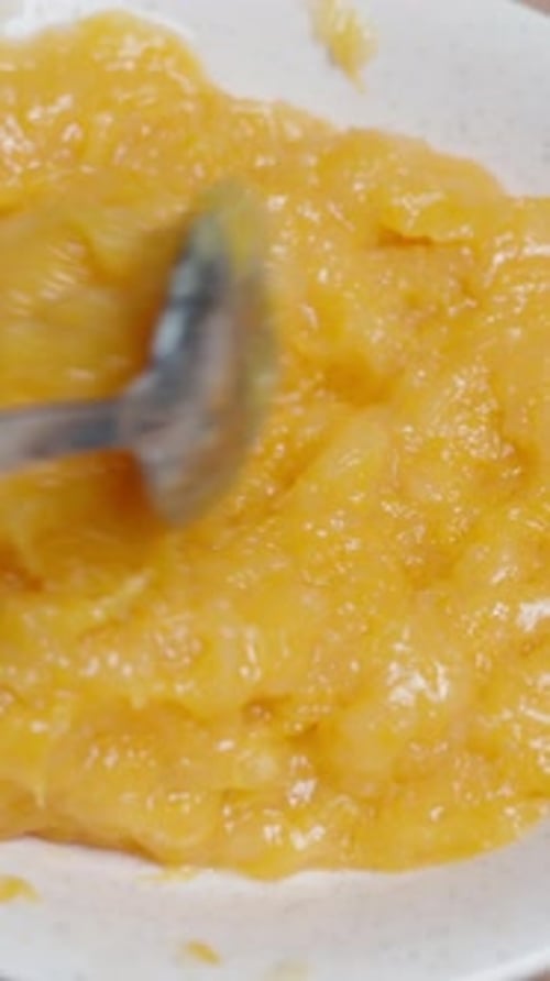 D'en haut, une femme remue la garniture à la compote d'orange pour le gâteau. Vidéo verticale.