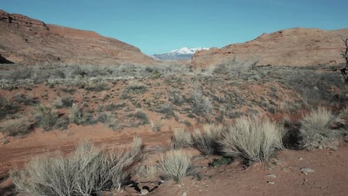 Low drone flight over barren Utah landscape with distant snowy mountain view