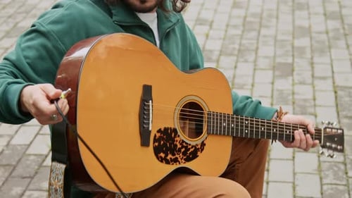 Musicien avec guitare branchant un cordon alors qu'il se prépare à chanter dans un parc