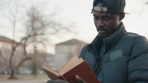 Close Up Of Man Reading Book Outdoors In Evening Light
