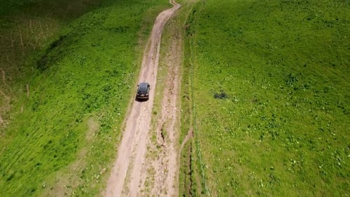 Drone: flies behind a car along the valley of the mountains of Kyrgyzstan