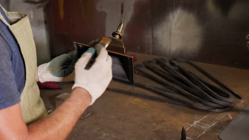 A Blacksmith Man Paints Scratches and Roughness on the Bell with Gold Powder