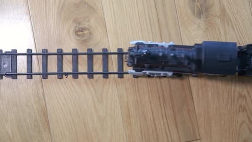 Top down view on plastic toy train riding railway emitting steam